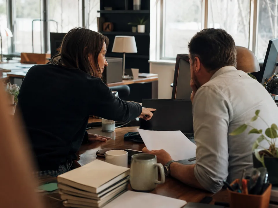 Head of content comparing marketing software options with a colleague at a cluttered desk