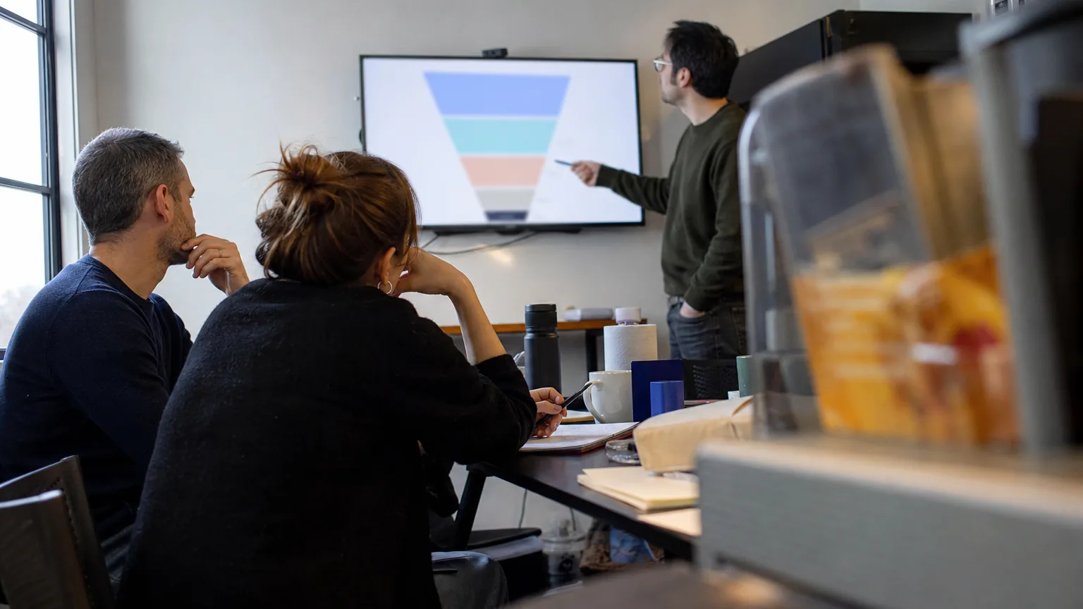 SaaS growth team at a standup reviewing funnel numbers on a screen