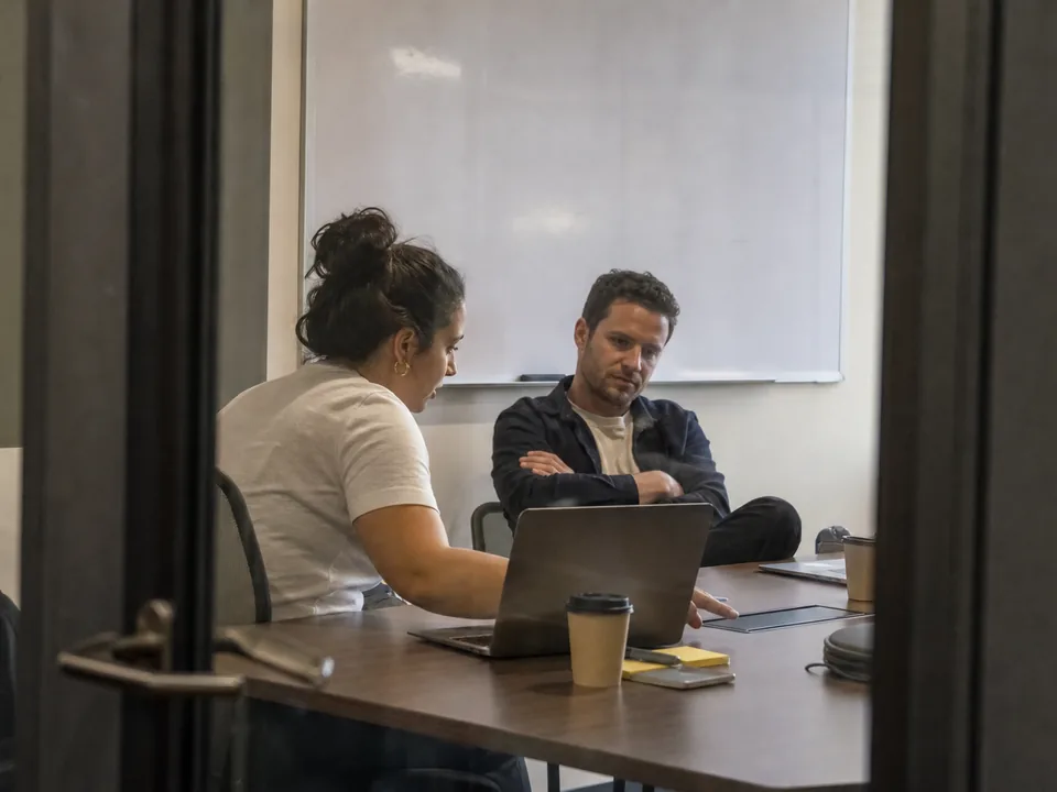 Two marketing managers debating which marketing software to switch to in a small meeting room