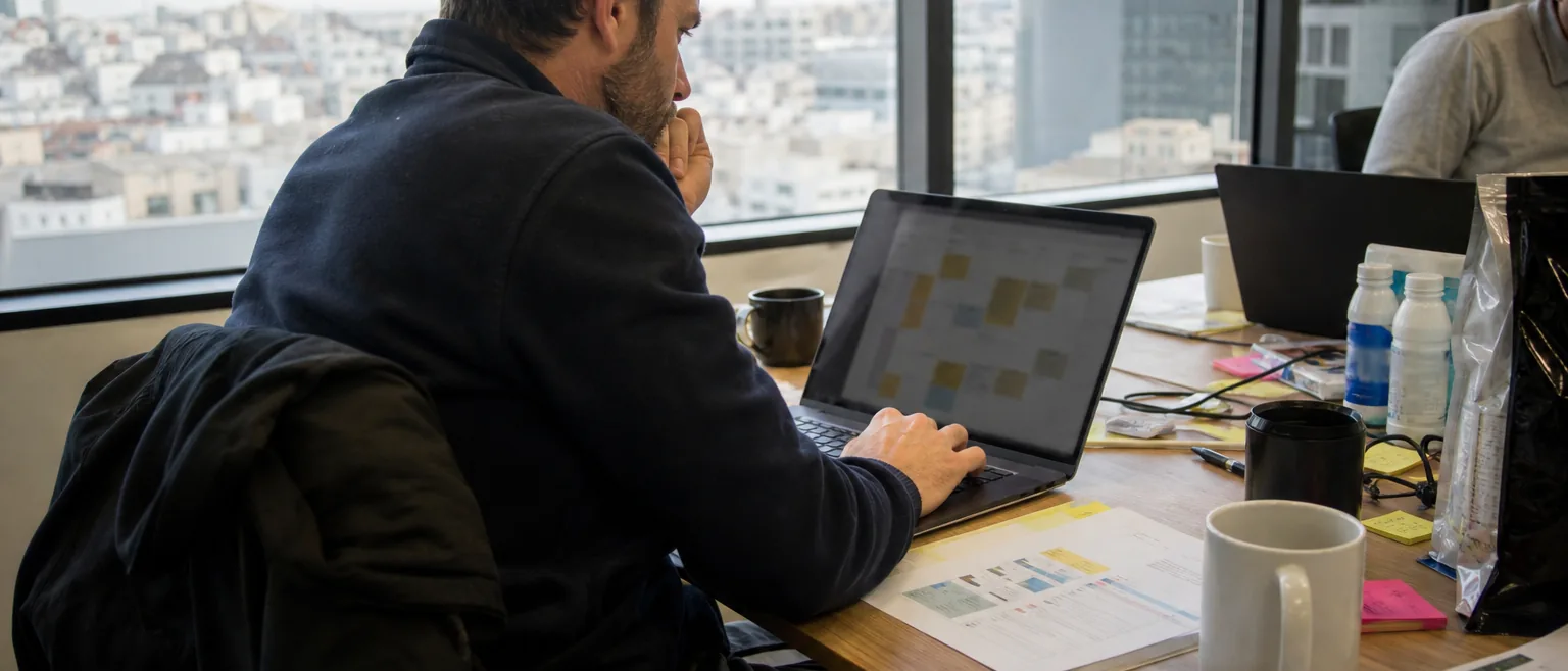 Small business owner working through the weekly marketing plan on a laptop at a shared office desk